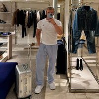 Person taking a mirror selfie in a clothing store with suitcases and shoes around