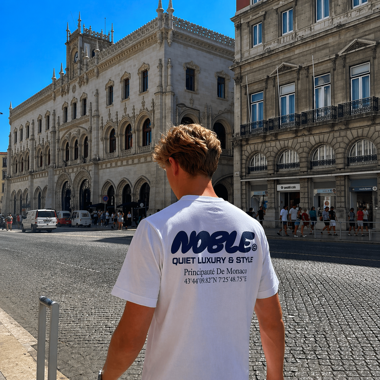 Person wearing a white t-shirt with 'Noble' branding in an urban setting.